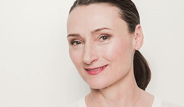 Frau mit dunklem Zopf lächelt in die Kamera vor hellem Hintergrund – Portrait der Referentin Birgit Seifarth, die das Achtsamkeitsformat bei den DATAGROUP Gesundheitswochen begleitet.