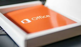 Nahaufnahme einer Microsoft Office Verpackung in Orange mit weißem Logo, liegend in einer geöffneten Schachtel.