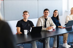 DATAGROUP Mitarbeitende  sitzen gemeinsam am Tisch mit Laptop.