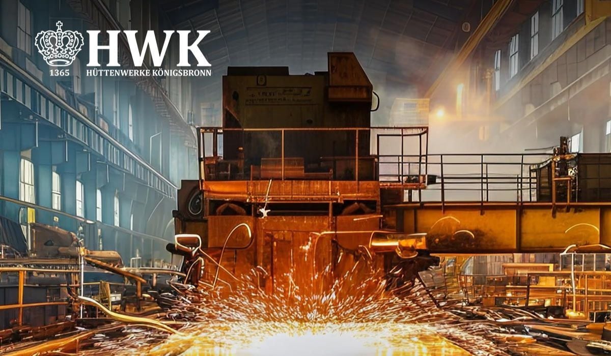Innenaufnahme einer großen Industriehalle mit schweren Metallverarbeitungsanlagen. Im Vordergrund sprühen helle Funken über einer metallischen Arbeitsfläche. Im Hintergrund sind Stahlträger, Plattformen und Maschinen in einer stark beleuchteten Produktionsumgebung zu sehen. Oben links befindet sich das Logo der Hüttenwerke Königsbronn (HWK).