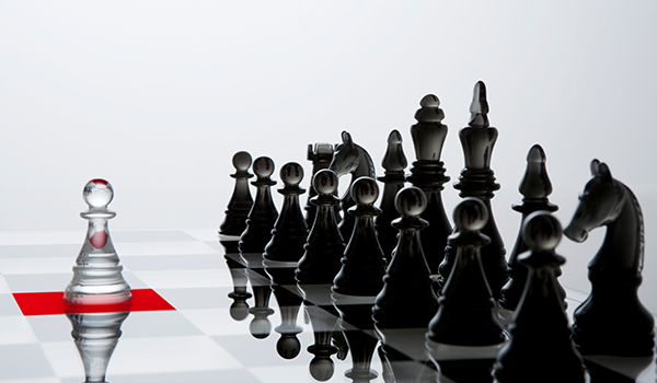 White pawn placed in front of a black chess set, symbolizing strategy, competition, and decision-making.