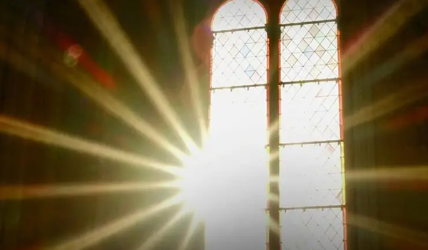 Sonnenlicht strömt durch ein hohes, gewölbtes Buntglasfenster mit einem Rautenmuster und erzeugt helle Strahlen und einen Linseneffekt in einem schwach beleuchteten Raum.