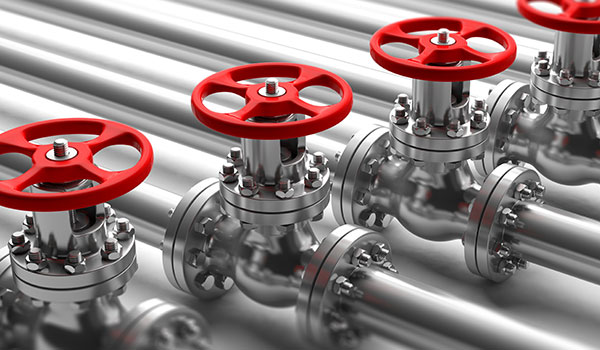 Mehrere glänzende Metallrohre mit roten Handventilen.