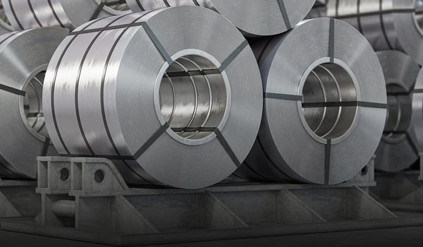 Mehrere große, silbrig glänzende Aluminium‑Coils liegen gestapelt in einer Industriehalle