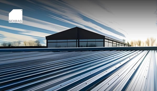 Metallisches Dach mit parallel verlaufenden Profilblechen im Vordergrund, dahinter ein modernes Industrie- oder Hallengebäude vor einem Himmel mit langgezogenen Wolken. Oben links ist ein quadratisches Logo mit dem Schriftzug „SCHRAG“ zu sehen.