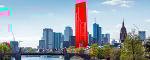 Blick auf die Frankfurter Skyline mit Hochhäusern des Bankenviertels, dem Main im Vordergrund und einer stilisierten roten Wolkenkratzer-Silhouette unter bewölktem Himmel