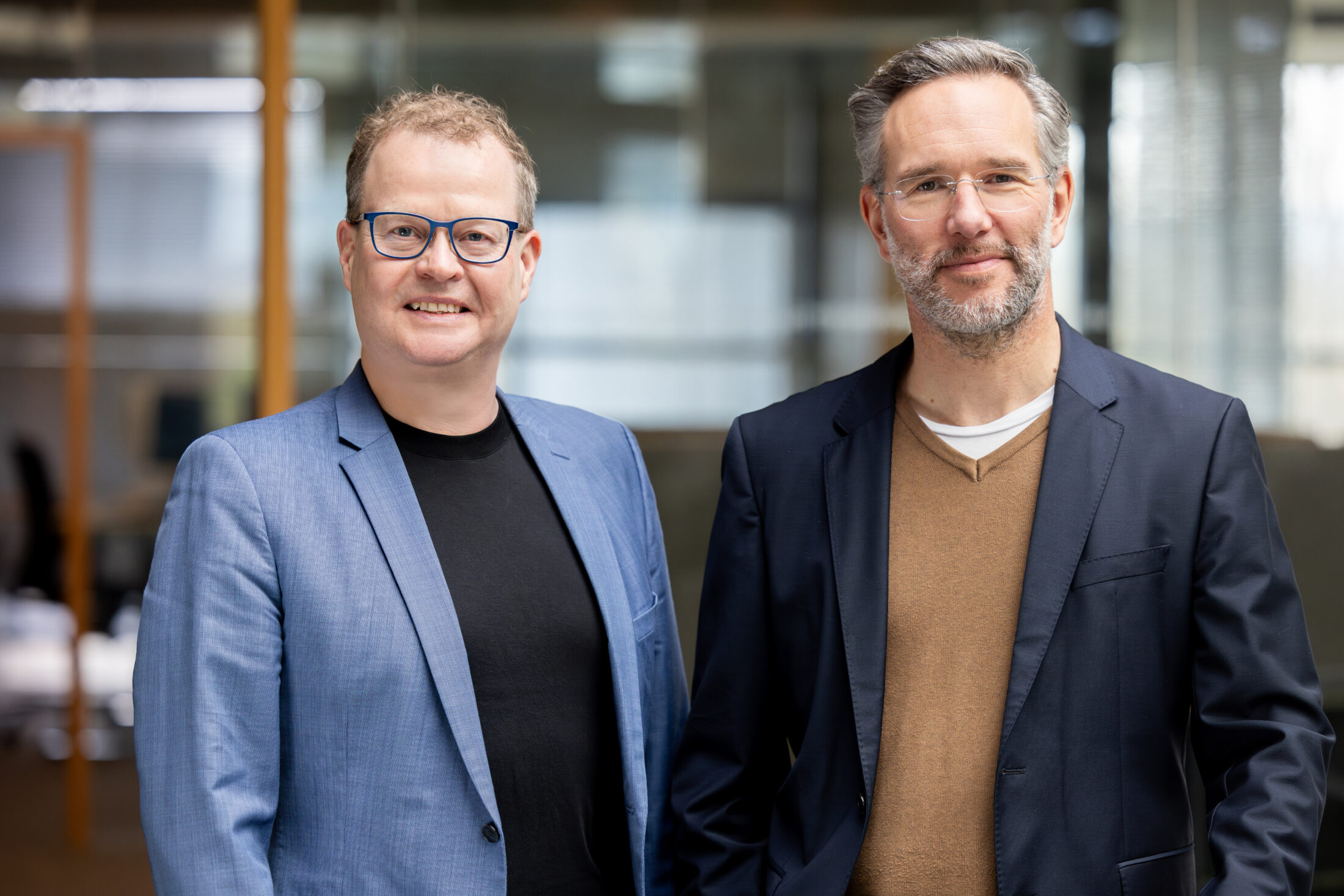Photo of Mark Schäfer (left) and Andreas Baresel (right) in front of a glass facade
