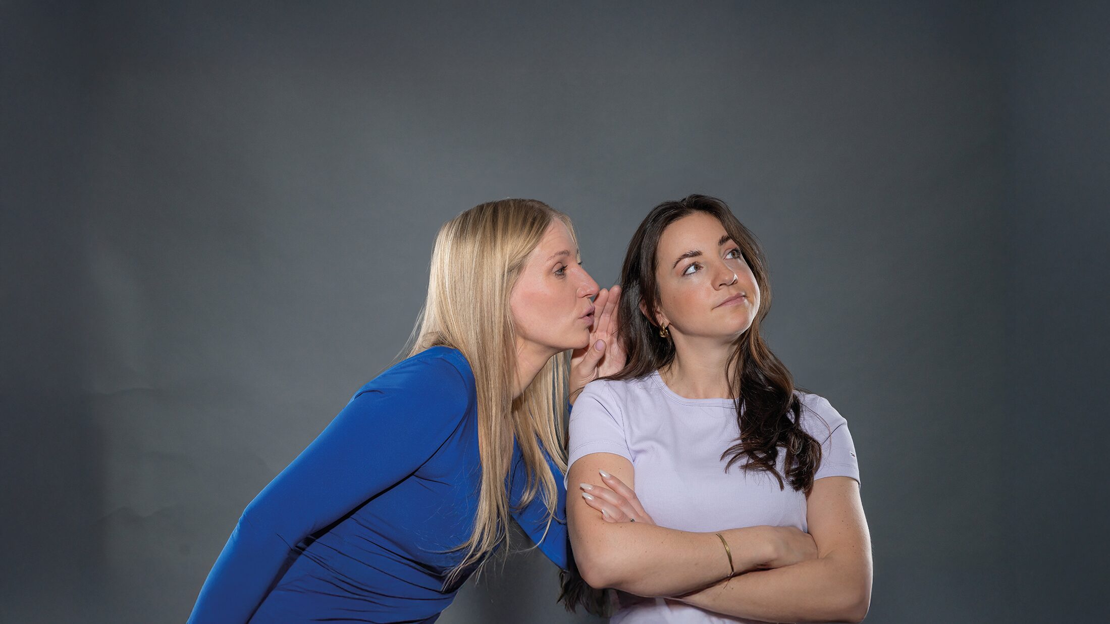 Zwei Frauen beim Podcast-Shooting „Unboxing IT“, eine flüstert der anderen ins Ohr