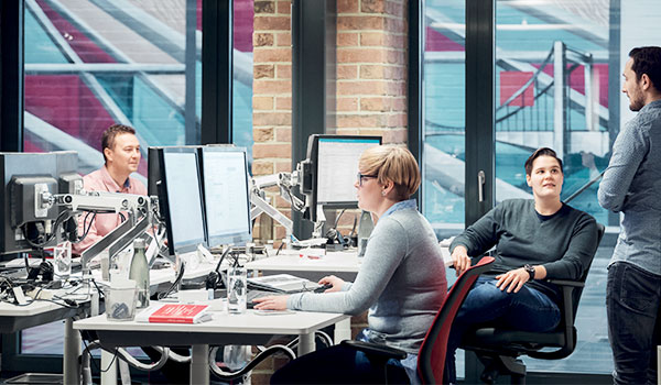Mehrere Mitarbeitende von DATAGROUP arbeiten in einem modernen Büro gemeinsam an ihren Bildschirmen