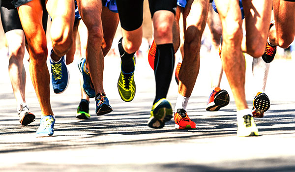 Beine und Füße von Läufern in bunten Laufschuhen während eines Firmenlaufs