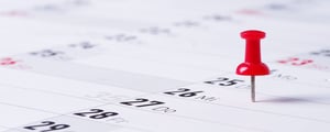 Roter Pin steckt in einem Kalender, Symbol für wichtige Termine