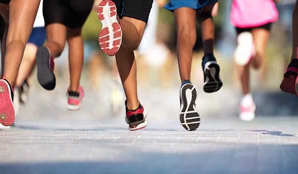 Runners in sports shoes running on the street, focus on legs and footwear.