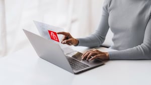 Person nutzt Laptop und tippt auf holografische Sicherheitsoberfläche mit rotem Schloss-Symbol – Key Visual für IT-Security Services.