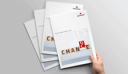 Mehrere Ausgaben des DATAGROUP Magazins liegen leicht versetzt auf einem Tisch. Eine Hand hält ein Exemplar mit dem Titel „IT’s Change“, dessen Cover das Wort „CHANGE“ aus Holzbuchstaben zeigt, wobei der Buchstabe „G“ rot hervorgehoben ist.