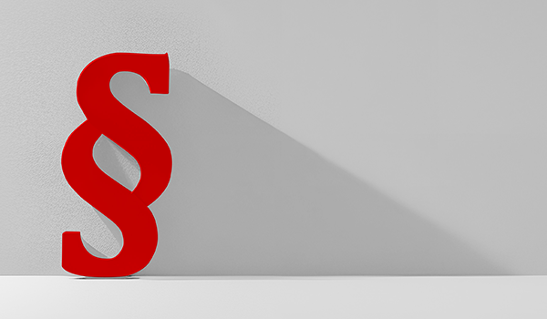 Ein rotes Paragraphen-Zeichen lehnt gegen eine graue Wand