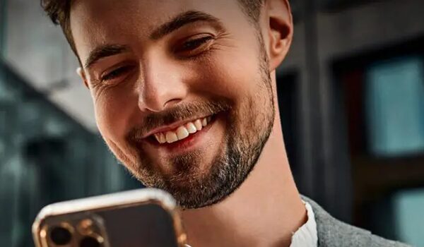 Close-up of a smiling man looking at his smartphone – key visual for the Deutsche Telekom reference.