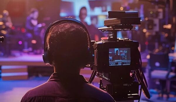 Kameraperson filmt eine TV‑Produktion in einem Studio, im Fokus stehen digitale Bewegtbildinhalte und moderne Medientechnik.