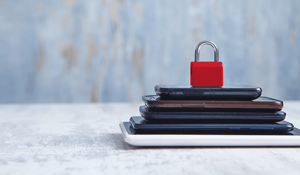 Stapel von Smartphones und Tablets, gesichert mit einem roten Vorhängeschloss. Symbol für IT-Sicherheit und Datenschutz in Microsoft 365.
