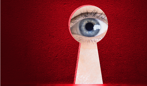 Fotografie eines Auges, das durch ein Schlüsselloch blickt – Symbol für IT-Sicherheit und Überwachung.