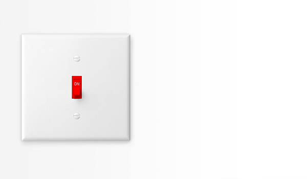 Nahaufnahme eines weißen Lichtschalters mit rotem Hebel in der Position ‚ON