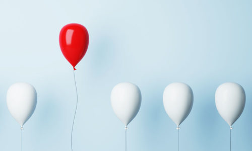 Aufsteigende weiße Luftballons, einer davon ist rot