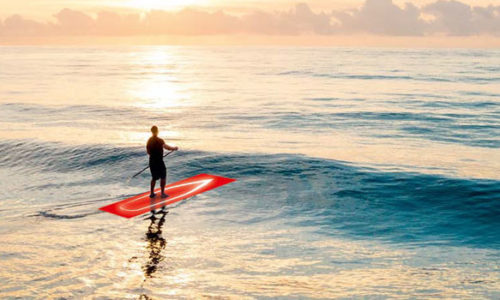 Stand-Up Paddler auf rotem Board paddelt ins Meer