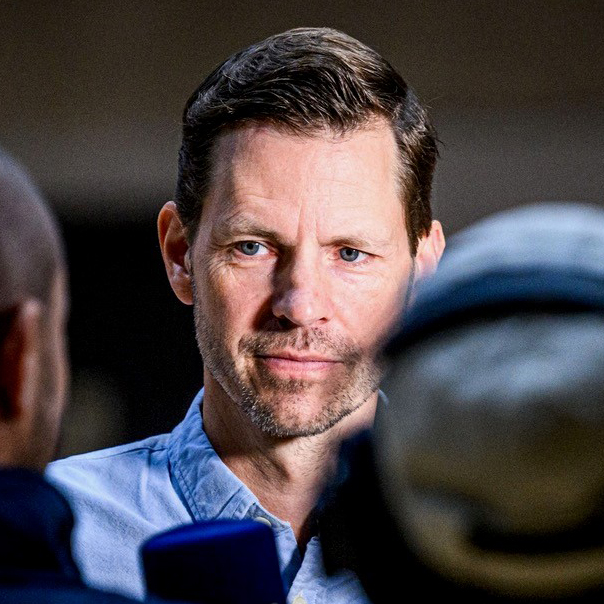 Mann mit kurzen Haaren und Hemd, der in einem Interview angesprochen wird.